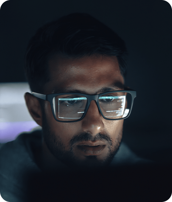 Homem olhando para tela de computador com reflexo nos óculos